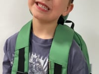 Video of boy showing the shoulder strap pocket of the green tractor jude&moo backpack