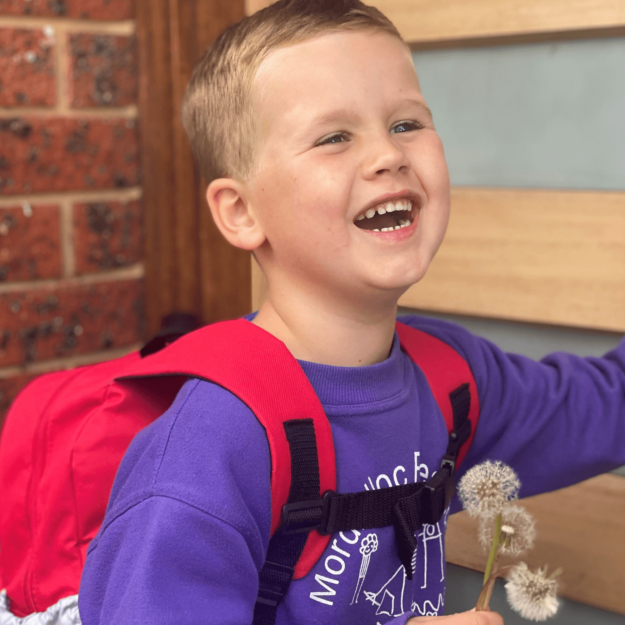 Boy laughing while wearing ambulance backpack.