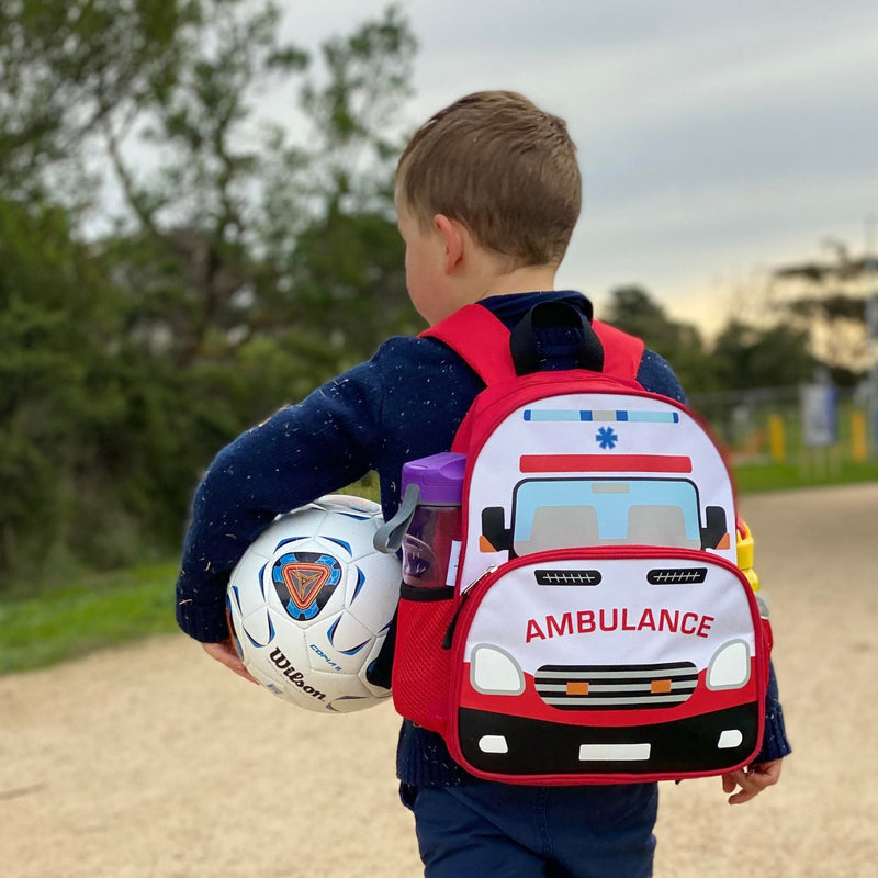 Boy wearing ambulance backpack while holding a soccer ball.